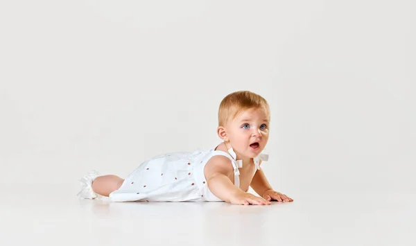 美しい赤ちゃん 小さな女の子 床に横たわるドレスのトッドラー そしてホワイトスタジオの背景に注意深く目を向けます 子供の頃の概念 新生児のライフスタイル Adのためのスペースをコピーする — ストック写真