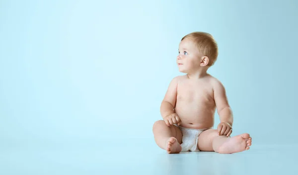 美しい小さな赤ちゃん おむつにおむつ 落ち着いて床に座って ライトブルーのスタジオの背景に目を向ける 子供の頃の概念 新生児のライフスタイル Adのためのスペースをコピーする — ストック写真