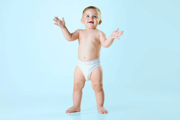 小さな赤ん坊の女の子の肖像画 おむつに立って ライトブルーのスタジオの背景に手をぶつけるトッドラー 陽気だったな 子供の頃の概念 新生児のライフスタイル Adのためのスペースをコピーする — ストック写真