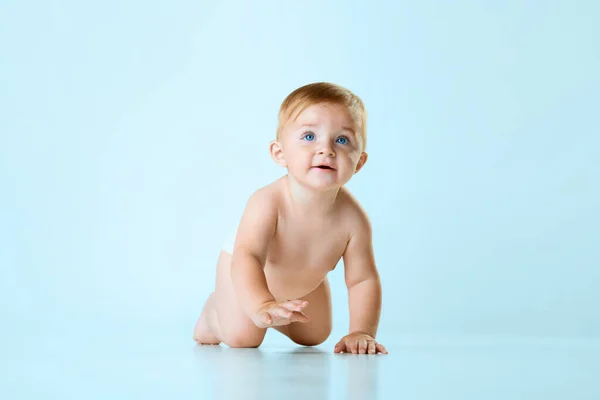 小さなかわいい赤ん坊 薄い青いスタジオの背景に対して床を這うおむつの幼虫 ブルーの目 子供の頃の概念 新生児のライフスタイル Adのためのスペースをコピーする — ストック写真