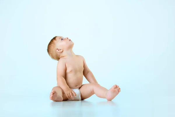 美しい小さな赤ちゃん ライトブルーのスタジオの背景に対して床に座っているおむつの中の幼児 穏やかな子供たち 子供の頃の概念 新生児のライフスタイル Adのためのスペースをコピーする — ストック写真