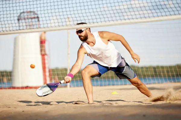 Young competetive man, athlete in singlasses playing paddle tennis, training outdoors on warm summer evening. Match. Concept of sport, leisure time, active lifestyle, hobby, game, summertime, ad