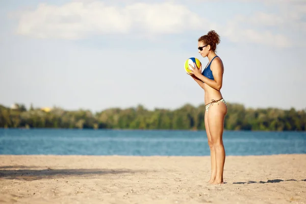 年轻的女运动员穿着泳衣在河边的沙滩上打沙滩排球 新鲜空气和训练 体育概念 积极健康的生活方式 业余爱好 — 图库照片