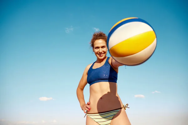 年轻的微笑女子拿着排球球 在蓝天的背景上摆姿势 户外暑期训练 体育概念 积极健康的生活方式 业余爱好 — 图库照片