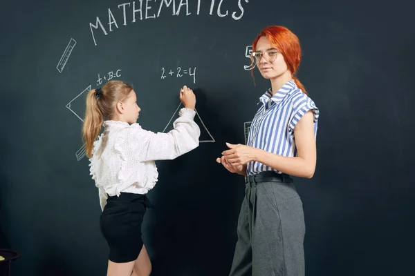 Молодая Женщина Преподаватель Математики Стоящая Доски Маленькой Девочкой Студенткой Решающая — стоковое фото