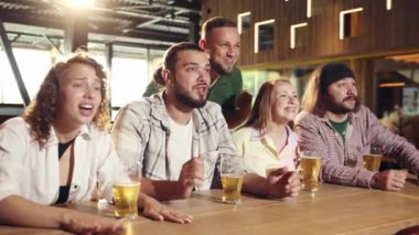 Neşeli insanlar, barda oturan arkadaşlar, dikkatle futbol maçı çevirisi izleyen, bira içen, eğlenen. Spor yarışması kavramı, hobi, yaşam tarzı, insani duygular, eğlence