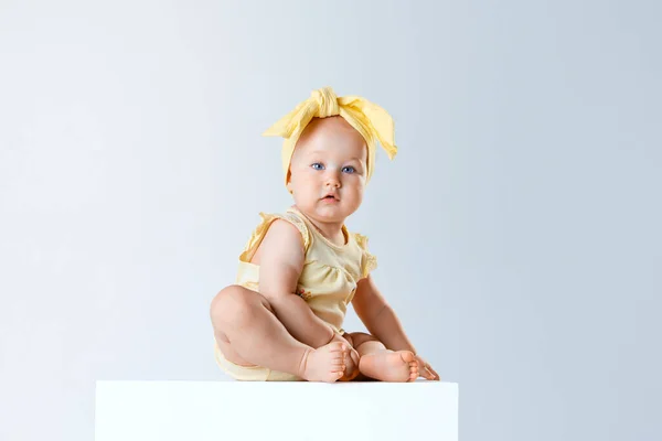 かわいい 柔らかい赤ん坊の少女 青い目を持つ幼児は 灰色のスタジオの背景に座って黄色い服やアクセサリーを着ています 子供時代 ケアの概念 Adのためのスペースをコピーする — ストック写真