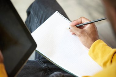 Erkek ellerinin kalem tutarken, not defterine not alırken video dersleri dinlerken, online toplantı yaparken yakın plan görüntüsü. İş ve eğitim kavramı, serbest meslek, modern yaşam tarzı