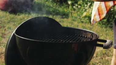 Adam evde barbekü yapıyor, bahçede, dışarıda. Bifteği ızgaraya koyuyorum. Sıcak bir yaz gününde yemek pişirmek. Yaz pikniği kavramı, yemek, zevk, parti, aşçılık