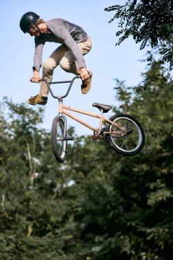 Spor bisikleti süren genç adamın dinamik görüntüsü, BMX. Yüksekten atlamak, numaralar yapmak, parkta antrenman yapmak. Aktif yaşam tarzı, spor, ekstrem, dinamik, hobi kavramı