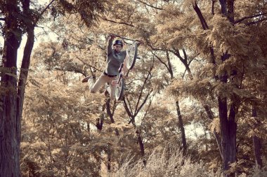 Parkta bisiklet eğitimi alan genç bir adam BMX bisikletiyle havada numaralar yapıyor. Eğitim aktivitesi. Atlıyorum. Aktif yaşam tarzı, spor, ekstrem, dinamik, hobi, serbest stil kavramı