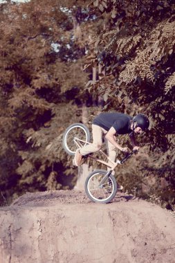 Ön tekerlekte duruyor. Genç anne binicilik, BMX bisikleti eğitimi ormanda tepelerde, numaralar. Ön tekerde dönüyor. Aktif yaşam tarzı, spor, ekstrem, dinamik, hobi, serbest stil kavramı