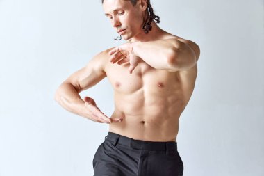 Gri stüdyo geçmişine çıplak poz veren yakışıklı olgun bir adam. Kaslı erkek vücudu, kabartma gövdesi. Erkeklerin güzellik anlayışı, vücut bakımı, moda, sağlık, sağlıklı yaşam tarzı, reklam