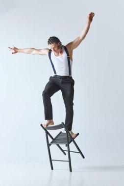 Yaşam dengeni koru. Gri stüdyo arka planına karşı sandalyede poz veren kaslı vücutlu yakışıklı olgun bir adamın portresi. Erkeklerin güzellik anlayışı, vücut bakımı, moda, sağlık, sağlıklı yaşam tarzı, reklam