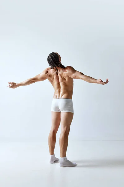 在灰色工作室的背景下 后视镜下的男人穿着内裤摆出一副赤身裸体的样子 健康的身体 男性美的概念 身体护理 健康的生活方式 — 图库照片