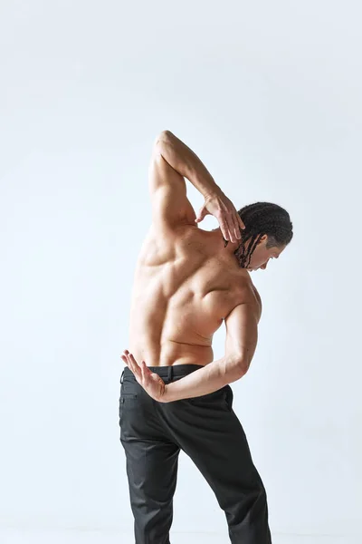 在灰色工作室的背景下 一个穿着黑色裤子的赤身裸体男子的后视镜图像 肌肉的身体 男性美的概念 身体护理 健康的生活方式 — 图库照片