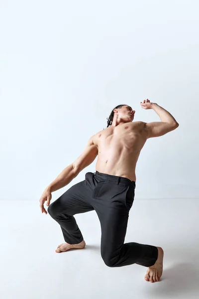 Atletische Man Poseren Beweging Shirtloos Broek Tegen Grijze Studio Achtergrond — Stockfoto