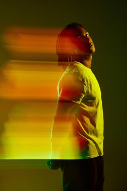 Neon ışıkta yeşil arkaplanda poz veren yakışıklı bir gencin portresi. Karışık ışık efekti. Dijitalleştirme. Sanat, moda, modern tarz, siber punk, fütürizm, reklam