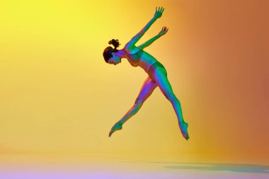 Talented, flexible young woman dancing contemp in underwear against gradient yellow orange background in neon light. Concept of modern dance style, hobby, art, performance, lifestyle, ad clipart
