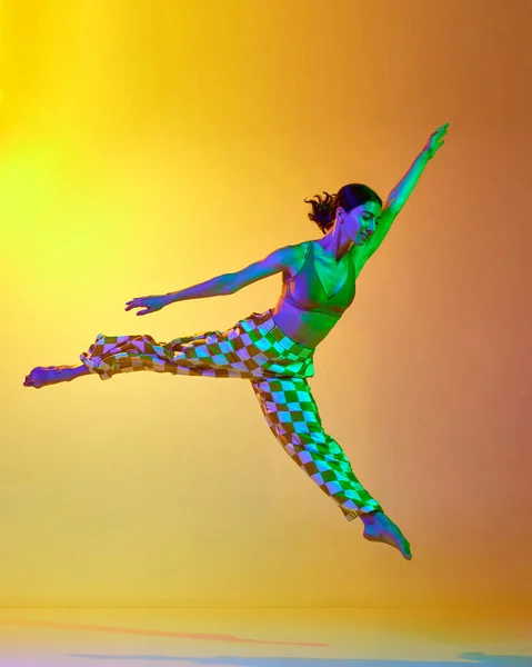 优雅的年轻女子 专业的舞蹈演员在运动中 在霓虹灯下 在渐变的黄色橙色背景下跳舞 现代舞风格 生活方式 广告的概念 — 图库照片
