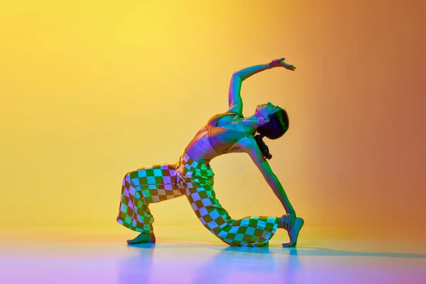 在霓虹灯下 一个柔韧 艺术的年轻女子在渐变的黄色背景下跳舞的动态图像 现代舞风格 生活方式 广告的概念 — 图库照片