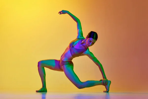 穿着内衣的有艺术天赋的年轻女子在霓虹灯下与渐变的黄色橙色背景跳舞 现代舞风格 生活方式 广告的概念 — 图库照片