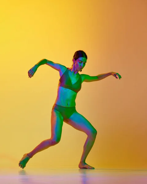全长的年轻女子形象 专业舞者在运动 内裤跳舞与渐变黄色橙色背景的霓虹灯 现代舞风格 生活方式 广告的概念 — 图库照片