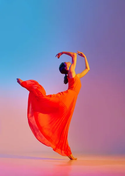 优雅的年轻女子穿着红色衣服 在霓虹灯下与深浅的五颜六色背景相映成趣 现代舞风格 生活方式 广告的概念 — 图库照片