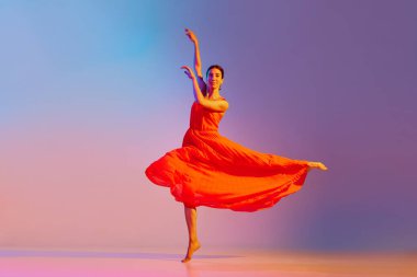 Talented, beautiful young woman in elegant red dress dancing against gradient multicolored background in neon light. Concept of modern dance style, hobby, art, performance, lifestyle, ad clipart