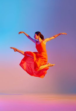 Klasik ve modern. Zarif genç bayan neon ışıkta, rengarenk arka plana karşı elbiseyle dans ediyor. Modern dans stili kavramı, hobi, sanat, performans, yaşam tarzı, reklam