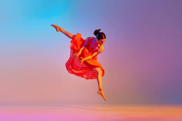 在霓虹灯下 穿着雅致的红色衣服在渐变的彩色背景下跳舞的年轻女性的动态形象 现代舞风格 生活方式 广告的概念 — 图库照片