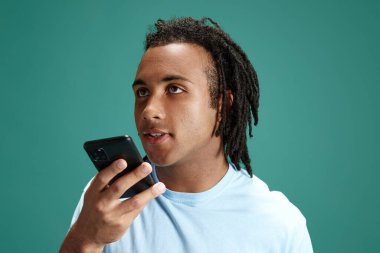 Genç Afrikalı bir adam cep telefonundan yeşil stüdyo geçmişiyle ilgili sesli mesaj kaydediyor. Arkadaşlarla iletişim. Gençlik kavramı, duygular, yaşam tarzı, moda, yüz ifadeleri, reklam