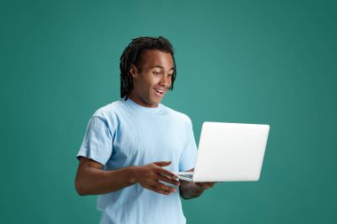 Genç çocuklar heyecan içinde dizüstü bilgisayara bakıyor ve yeşil stüdyo geçmişine gülümsüyor. Online eğitim. Gençlik kavramı, insan duyguları, yaşam tarzı, moda, yüz ifadeleri, reklam