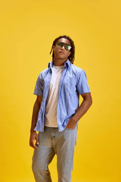 穿着条纹衬衫和太阳镜的年轻非洲男子的画像 站在黄色的工作室背景下 关于青年 人类情感 生活方式 面部表情 广告的概念 — 图库照片