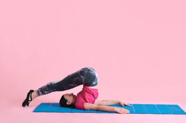 Esnek vücut. Olgun bir kadın spor salonu eğitimi, vücudu pembe stüdyo geçmişine karşı esnetiyor. Spor anlayışı, sağlıklı yaşam tarzı, fitness, vücut bakımı, sağlık, reklam