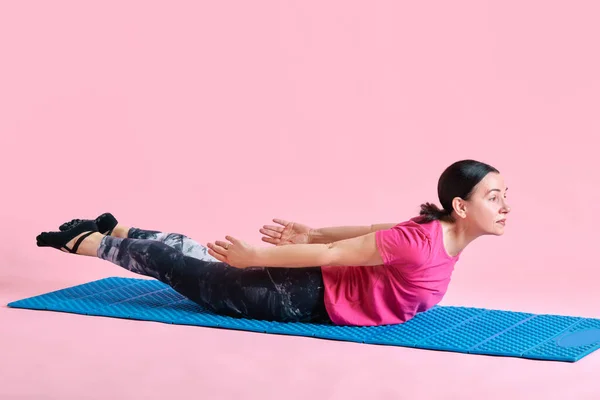 强壮的背练习 成熟女人躺在健身垫上 在粉色工作室的背景下接受训练 健康生活方式 身体护理 广告等概念 — 图库照片