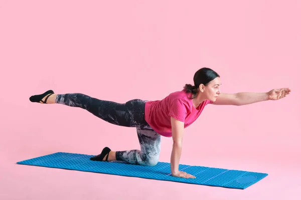 ピンクのスタジオの背景に対するフィットネスマットのスポーティブで健康で成熟した女性のトレーニング 強力な手 プレス スポーツ 健康的なライフスタイル フィットネス ボディケア ウェルネス 広告のコンセプト — ストック写真