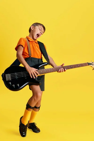Känslomässig Pojke Barn Snygga Kläder Spelar Gitarr Mot Gul Studio — Stockfoto