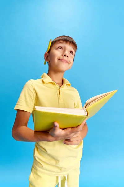 Emotive School Boyholding Book Dreamy Positive Face Blue Studio Background — Stock Photo, Image
