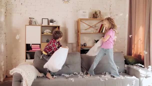 陽気で 幸せで 笑顔の小さな子供たち 男の子と女の子 リビングルームの家でソファーで枕ゲームをしている兄弟 子供時代 愛とケアの概念 — ストック動画