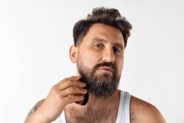 Beyaz stüdyo geçmişine karşı özel bir fırçayla sakallı yakışıklı, olgun bir adam. Erkeklerin güzelliği, cilt bakımı, kozmetoloji, sağlık ve sağlık kavramı. İlan için alanı kopyala