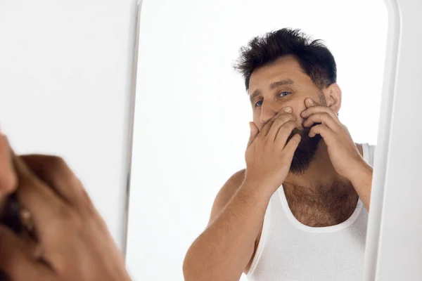 成熟的男人照镜子 检查脸的状况和挤压粉刺 家庭温泉 男性美感 皮肤护理 健康和健康的概念 广告的复制空间 — 图库照片