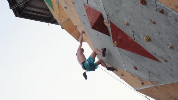 アスレチックで強く シャツのない若者が屋外でトレーニングし 人工的な岩壁を登ります 極端なスポーツ アクティブなライフスタイル 強さの概念 — ストック動画