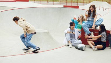 Neşeli insanlar, arkadaşlar, kaykay parkında buluşan gençler, eğleniyorlar, kaykaya biniyorlar, konuşuyorlar. Gençlik kültürü, spor, dinamik, aşırı, hobi, eylem ve hareketler, arkadaşlık kavramı