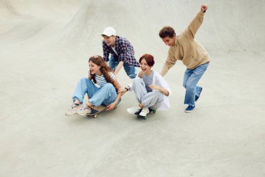 Bir grup neşeli arkadaş, kaykay parkında iyi vakit geçiren gençler, kaykaycılar, gülüşmeler. Neşe. Gençlik kültürü, spor, dinamik, aşırı, hobi, eylem ve hareket, arkadaşlık kavramı