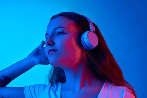 Girl Listening Music Headphones Blue Studio Background Neon Light Enjoyment — Stock Photo, Image