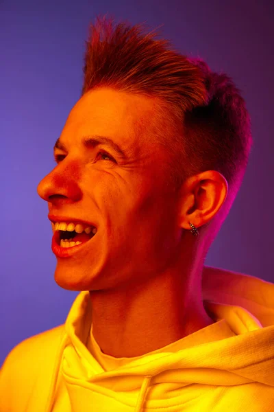風が顔に吹いている ネオンライトのグラデーションの紫色の背景にポーズするホワイトフーディーの若い男 人間の感情 ライフスタイル ファッション 広告の概念 — ストック写真