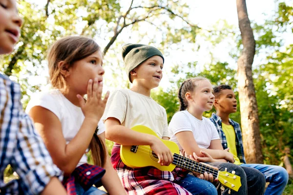 Crianças Felizes Sentadas Floresta Dia Ensolarado Tocando Guitarra Divertindo Caminhadas — Fotografia de Stock