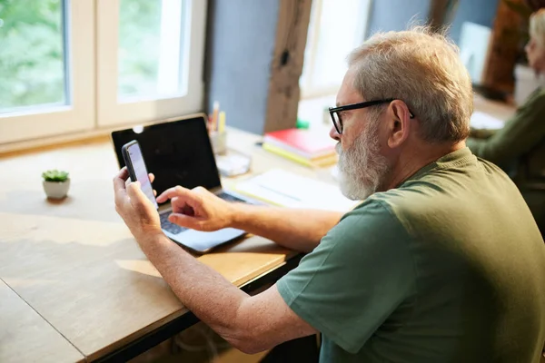 Старший Бизнесмен Сидит Столом Офисе Прокручивает Экран Мобильного Телефона Работает — стоковое фото