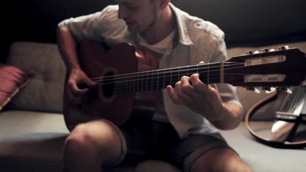 浪漫的约会晚上 年轻人坐在家里的沙发上弹奏吉他 享受快乐 业余爱好 创意生活方式 表演的概念 — 图库视频影像